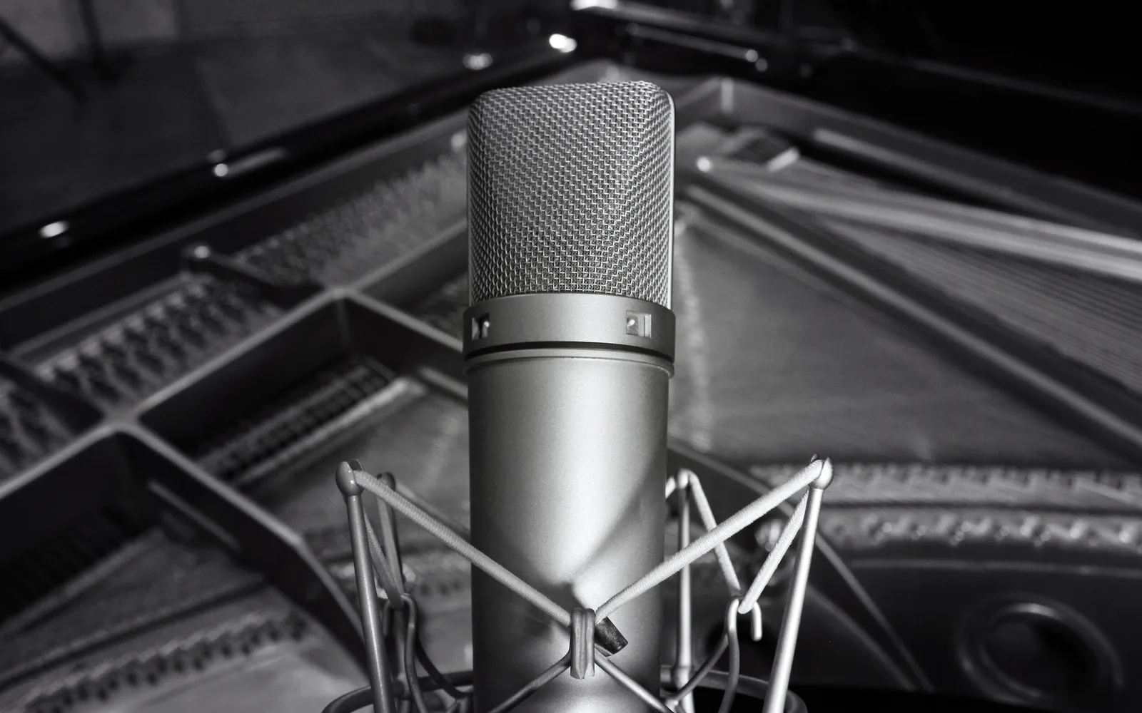 그랜드 피아노 위에 설치된 스튜디오용 콘덴서 마이크(Neumann U87)를 흑백으로 촬영한 사진
